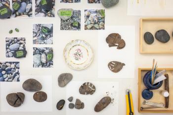 The surface of a table with rocks and papers on it