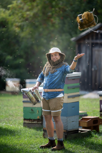 A male beekeeper with bees around his neck, face and shoulders