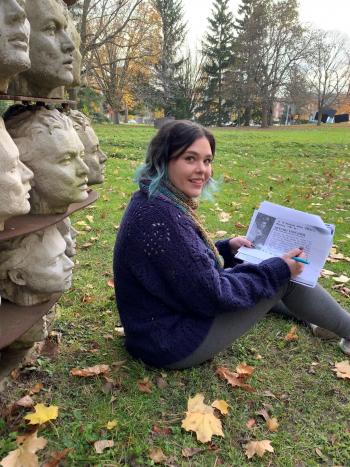 A woman sitting next to head sculptures